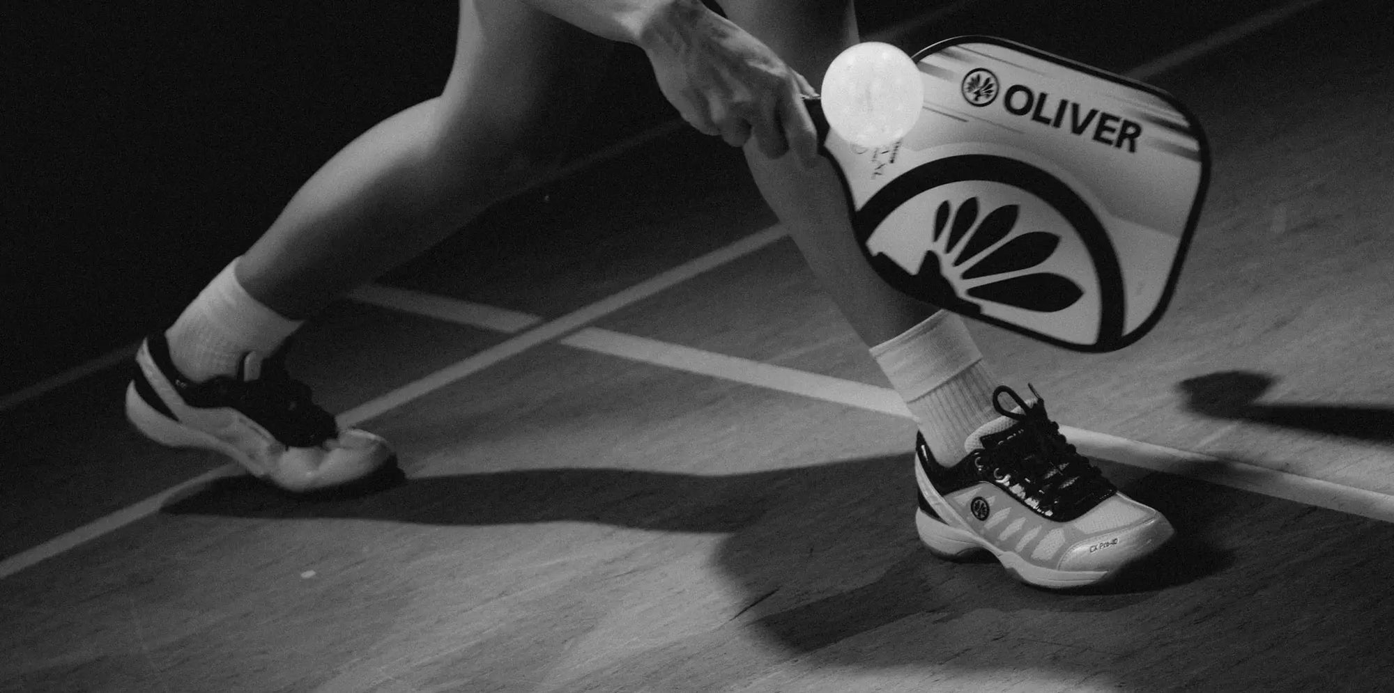 Pickleball player holding an OLIVER pickleball paddle on a court.