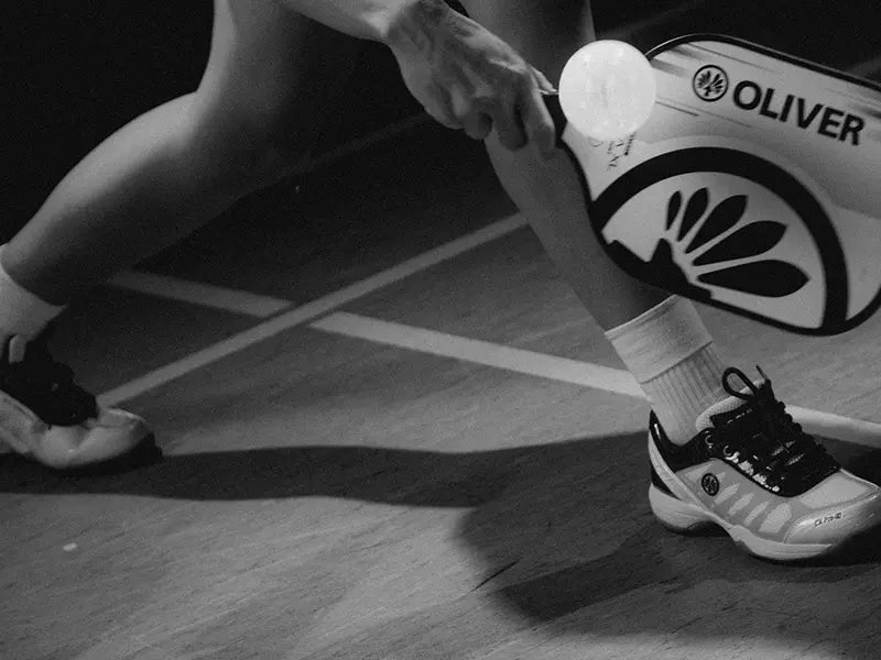 Pickleball player holding an OLIVER pickleball paddle on a court.