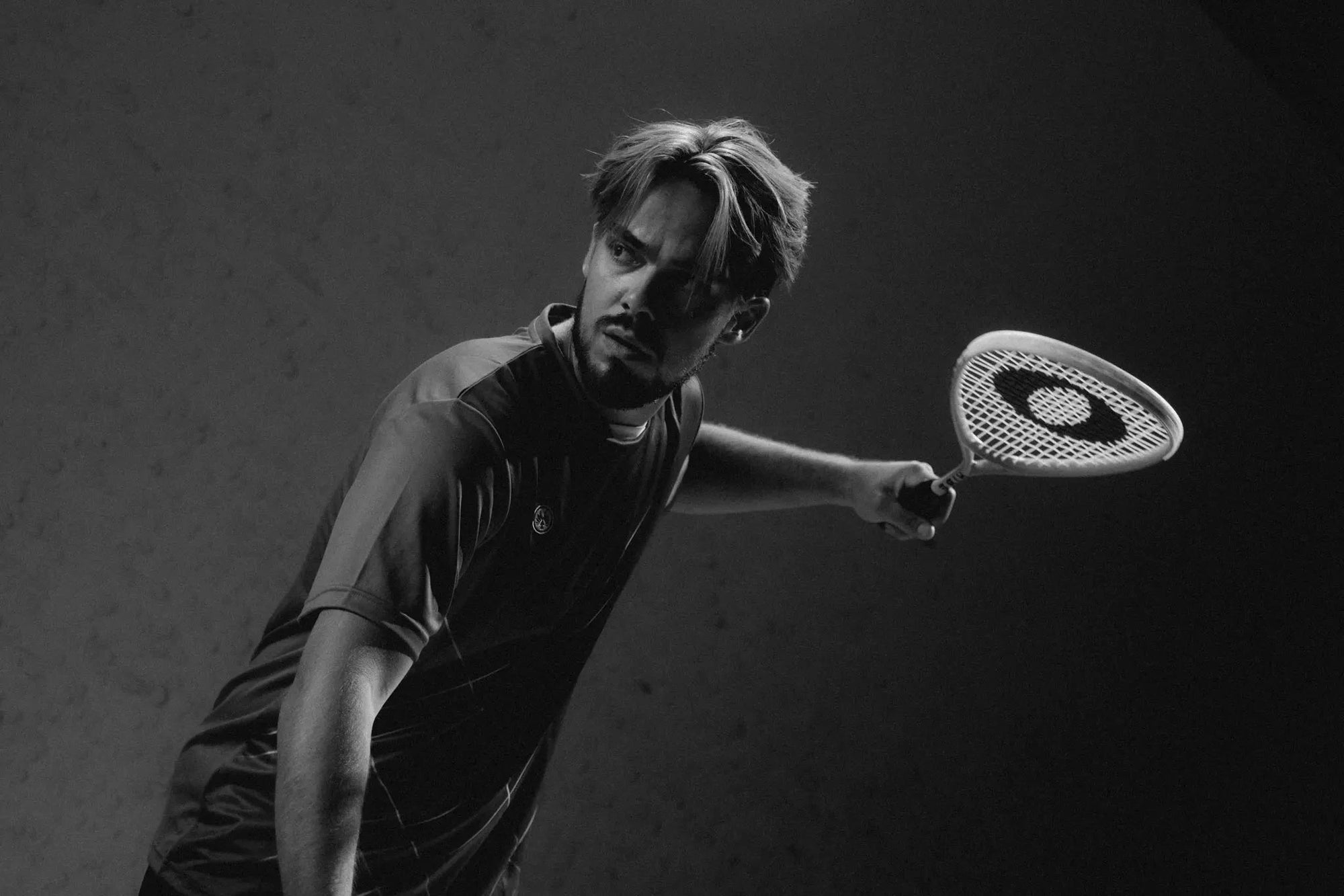 Sqaush player holding an OLIVER squash racket against a dark background